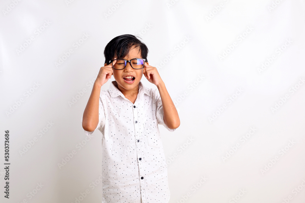 Stressed asian boy standing while holding his head. Isolated on white background Stressed asian boy standing while holding his head. Isolated on white background
