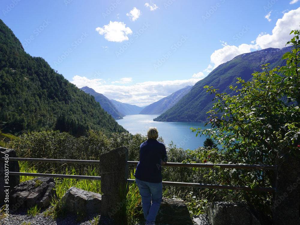 Eine Frau steht am Aussichtspunkt und schaut auf den Fjaerlandsfjord in Norwegen