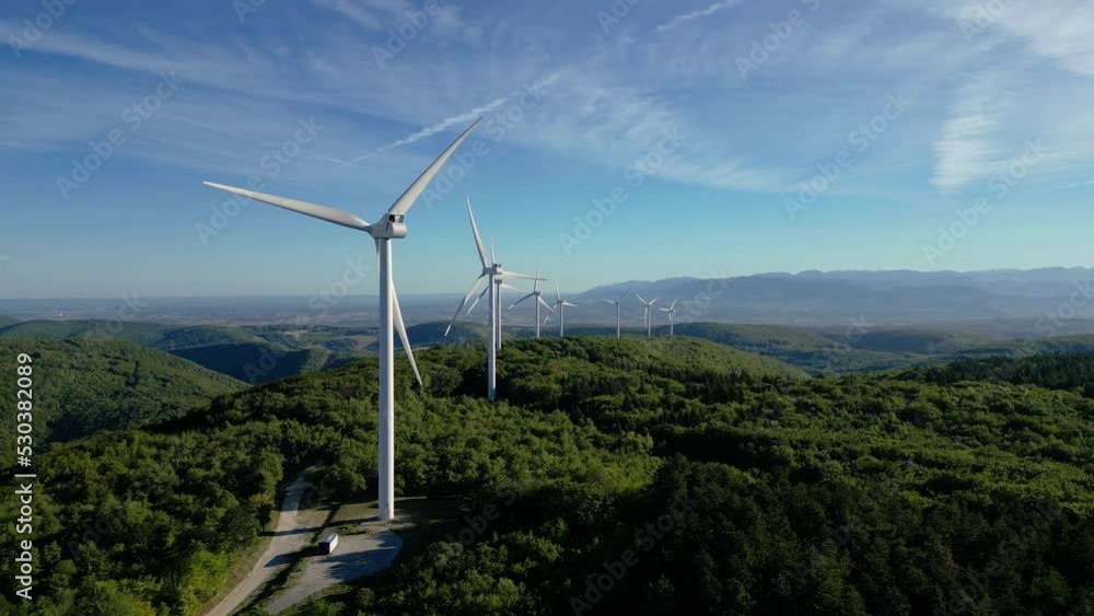 Turbine windmills for energy production. Renewable energy sources. Windmills situated on a hill overgrown with trees. Overlooking the surrounding mountains. Drome - South of France Turbine windmills for energy production. Renewable energy sources. Windmills situated on a hill overgrown with trees. Overlooking the surrounding mountains. Drome - South of France
