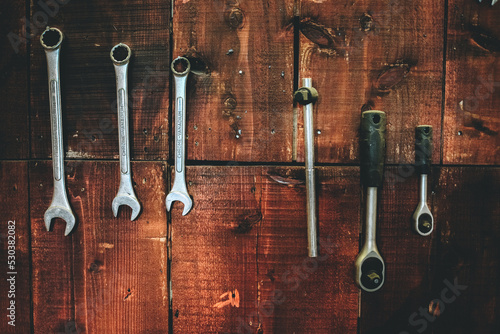 Set of wrenches hang on wooden wall in vintage garage with blank copy space
