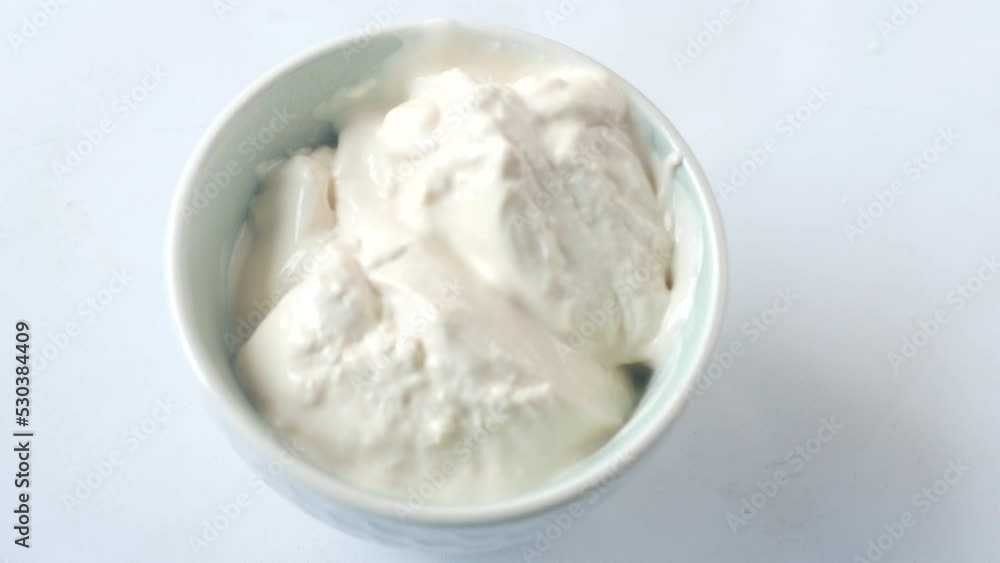 pouring milk cream in a container on white background pouring milk cream in a container on white background