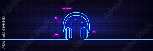 Neon light glow effect. Headphones line icon. Music listen sign. Musical earphones symbol. 3d line neon glow icon. Brick wall banner. Headphones outline. Vector