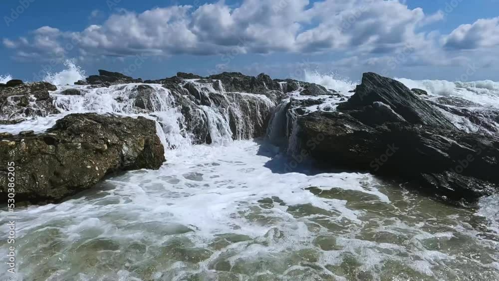 Ηigh waves crashing on a rock on a beach on a summer day. Pull back movement of the camera. Ηigh waves crashing on a rock on a beach on a summer day. Pull back movement of the camera.