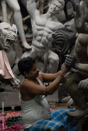 A man painting Durga idol with use of selective focus on a particular part of the man with rest of the man, the idol and everything else blurred. Kolkata, West Bengal, India - 11.09.2022