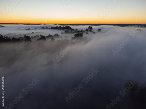 Pictures of the drone flight over the fog. River  forest  fields and meadows on a misty summer dawn. Summer.