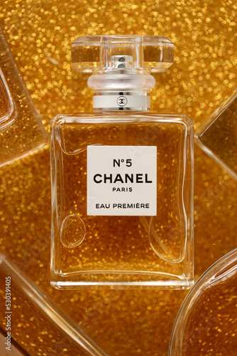 TERNOPIL, UKRAINE - SEPTEMBER 2, 2022 Chanel Number 5 Eau Premiere  worldwide famous french perfume bottle among other perfumes on shiny  glitter background in yellow colors Photos