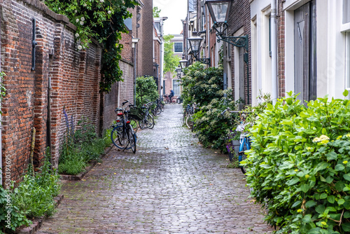 Foto Leiden Netherlands, brick wall building, lantern, cobblestone path, parked bicycle, green plants