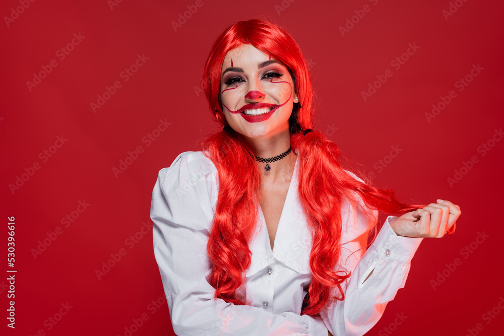 joyful woman with clown halloween makeup and bright hair isolated on red. joyful woman with clown halloween makeup and bright hair isolated on red.