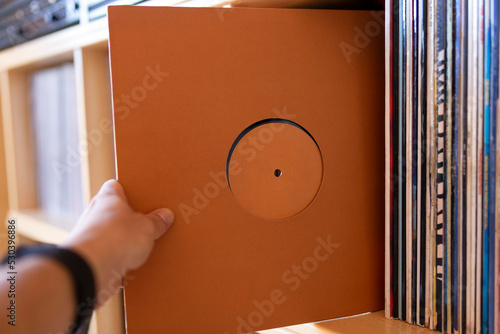 Close-up of person's hand holding a vinyl record from his record library. Music listening concept.