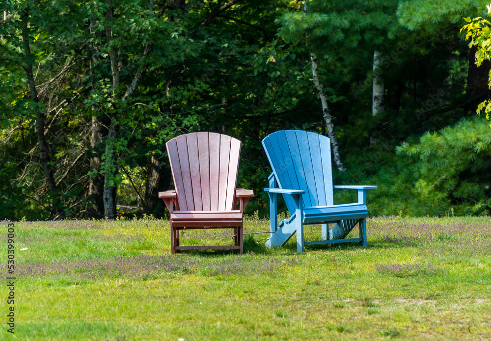 Colourful chairs at a park with trees in the background. Colourful chairs at a park with trees in the background.