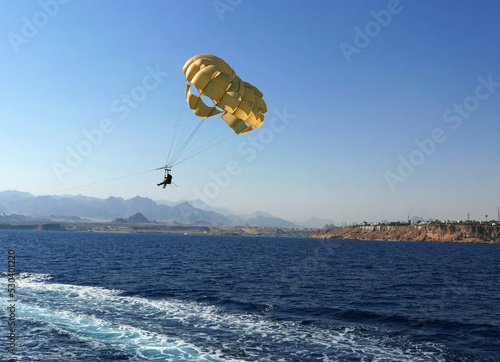 una mongolfiera gialla che si libra in aria sul mare photo