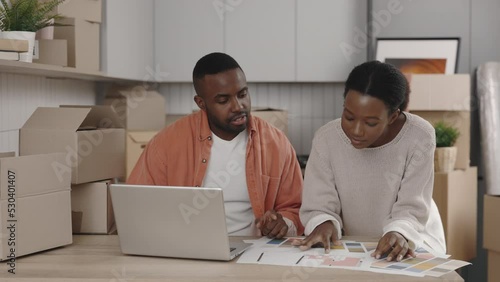 African american couple is choosing design for future interior. Happy couple talking about home design man checking avaible colours in the lap top. New home and moving concept. photo