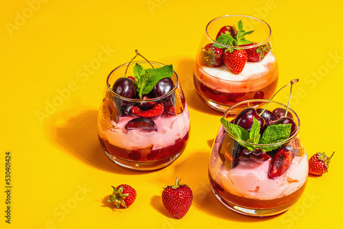 Delicious Italian dessert panna cotta with sweet cherry sauce, strawberry jam, fresh berries, mint