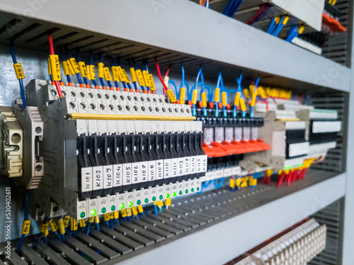 Row of fuses and relays installed in electrical cabinet automation system in industrial plant.