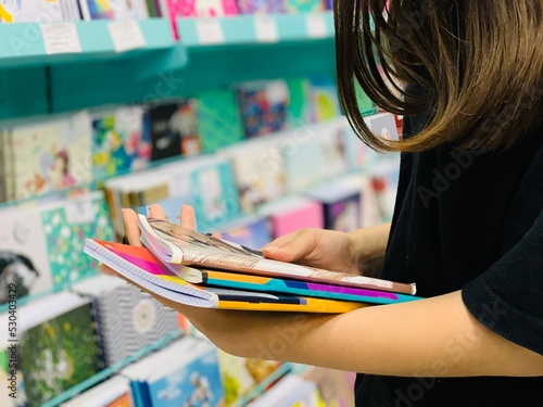 New normal retail shopping. Teenage blond girl wearing face mask choosing stationery in the retail shop. School supplies. Back to school shopping photo