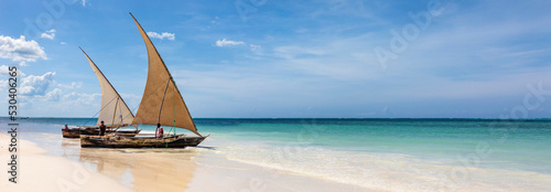 Sansibar, Dhows an einem Strand an der Küste der Insel. Boote im türkisfarbenes Ozean und blauer Himmel in Tansania, Panorama.