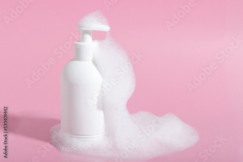 Cosmetics for face, body and hair care. Moisturizer, shampoo or facial cleanser on pink background with foam