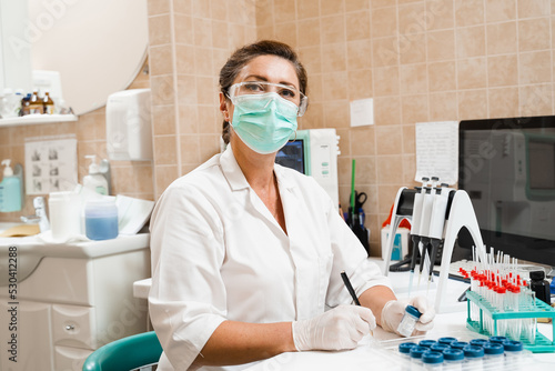 Laboratory assistant holds test tubes for gynecological and cytological analysis. Woman scientist working in medical lab.