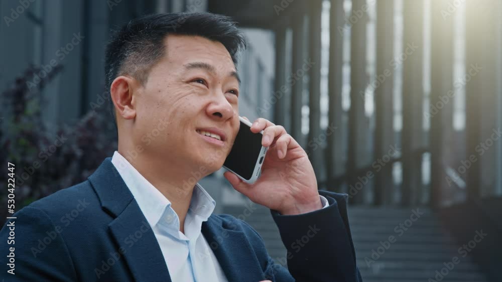 Portrait Asian adult 40s middle-aged man having phone talk outdoors smiling friendly talking on smartphone at street. Happy businessman call phone employee negotiation distant conversation outside Portrait Asian adult 40s middle-aged man having phone talk outdoors smiling friendly talking on smartphone at street. Happy businessman call phone employee negotiation distant conversation outside