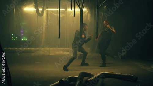 Playback male criminal or mafia member and police officer in body armor aggressively fighting in dim underground room illuminated by LED lamps. Action cinematic movie scene photo