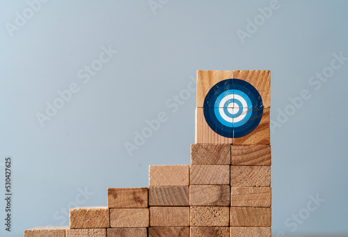 Cllose up photo of ladder made of wooden blocks and target sign on the top as a symbol of climbing or working hard for goals and targets. photo