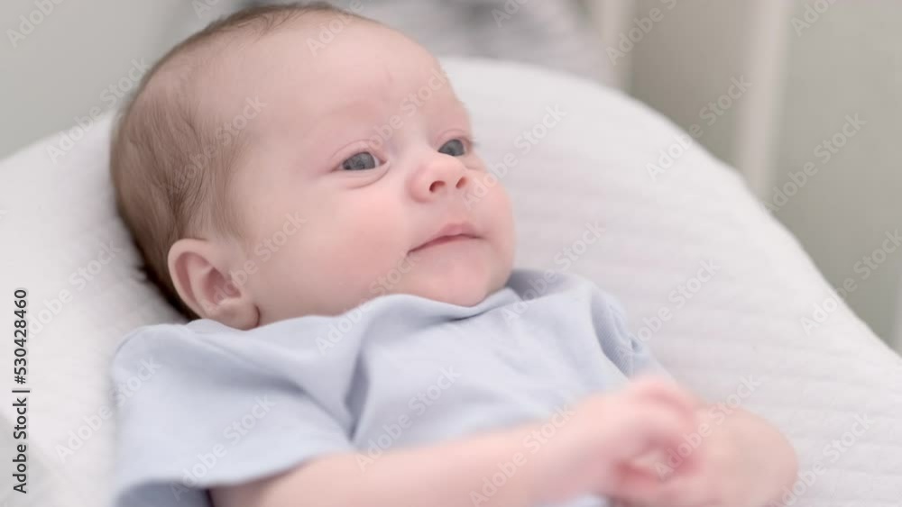 Portrait newborn baby boy lying in nursery cocoon with blue clothes on bed in bedroom at home, happy baby morning Portrait newborn baby boy lying in nursery cocoon with blue clothes on bed in bedroom at home, happy baby morning