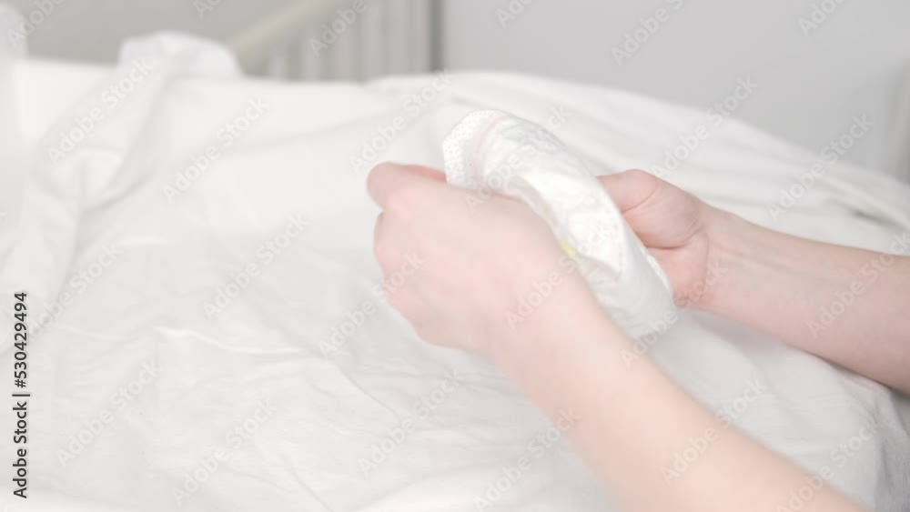 Mom folds used diaper to throw it in the trash, Mother changes diapers