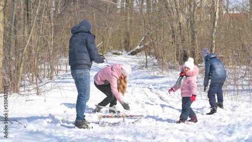 Happy family throw snowballs in a beautiful snowy park. Family enjoying winter day in forest. fun winter holidays