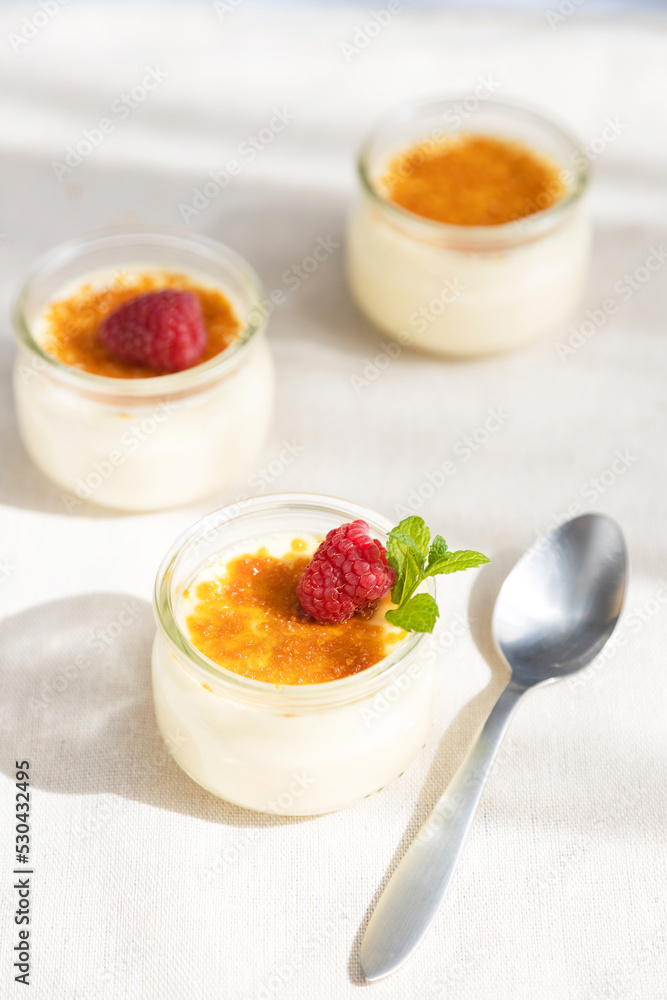 French dessert custard creme brulee with caramel crust, garnished with fresh berries. Traditional cuisine. Vertical photo French dessert custard creme brulee with caramel crust, garnished with fresh berries. Traditional cuisine. Vertical photo