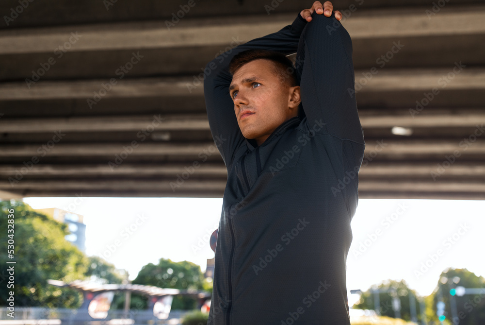 fitness, sport and healthy lifestyle concept - man stretching shoulder under bridge