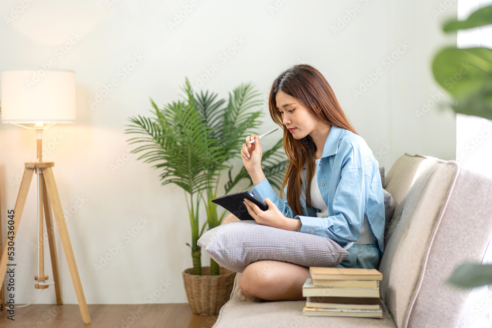 Young woman is analyzing strategy goal of business and taking notes on tablet while working on comfortable Young woman is analyzing strategy goal of business and taking notes on tablet while working on comfortable
