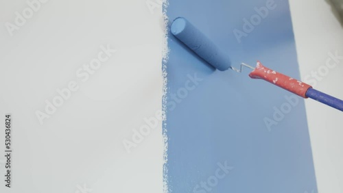 Parede branca sendo pintada de azul com rolo de pintura. 