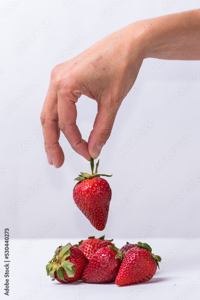 Obraz premium fingers choosing a red strawberry, fruit, healthy living, lifestyle
