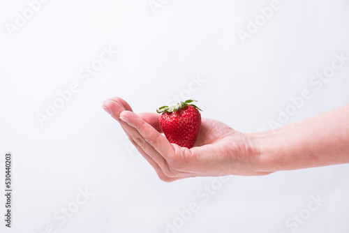 delicate hand holding a red strawberry, fruit, healthy living, lifestyle, healthy lifestyle