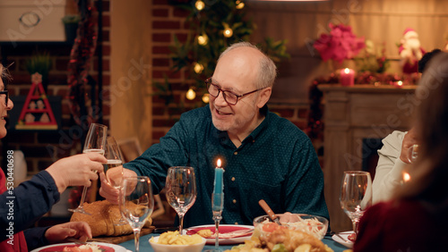 Happy senior couple talking to each other while enjoying Christmas dinner with loved ones.