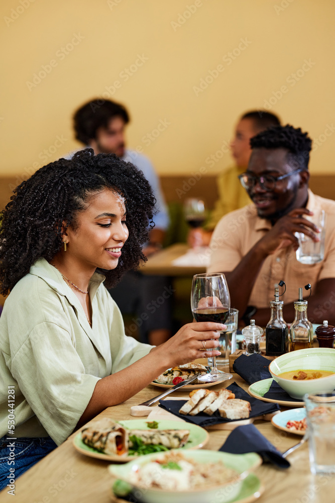 A smiling Hispanic girl is having dinner in a restaurant.