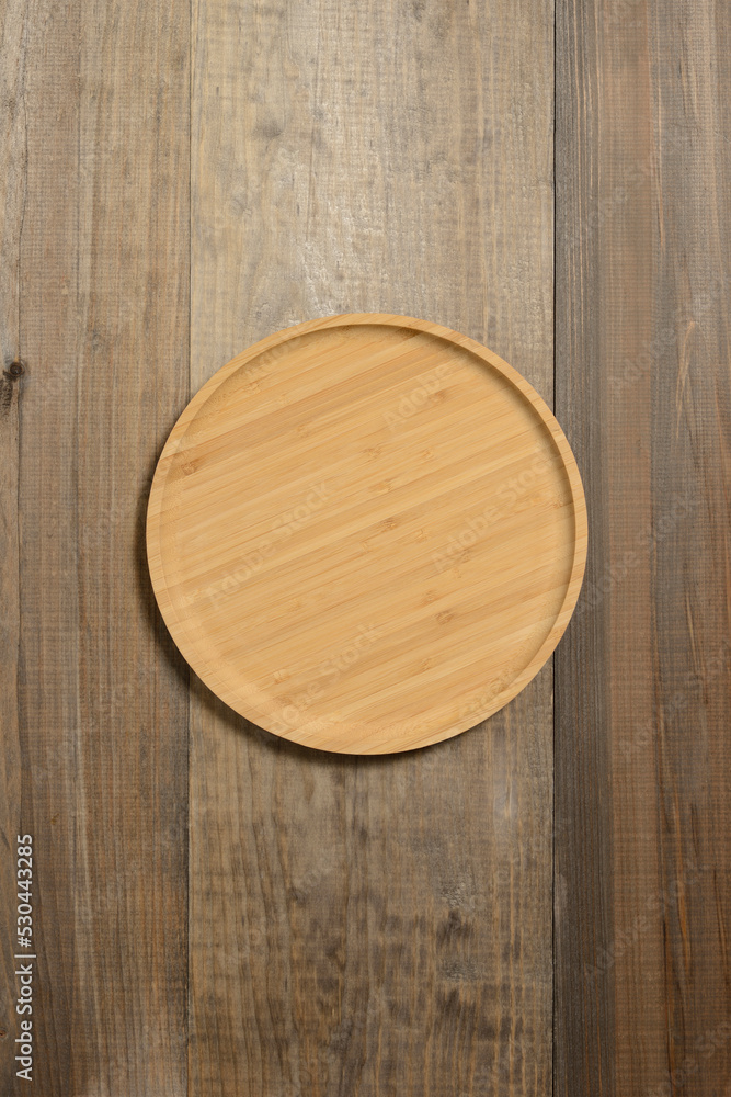 Plato redondo de madera sobre fondo de madera gris oscuro