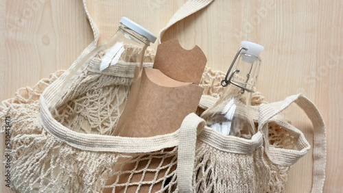 Reusable fabric shopping bag with glass bottles and paper eco-friendly packaging on the table. The concept of zero waste and the rejection of plastic in everyday life.