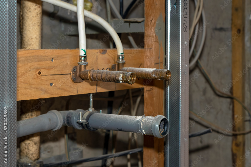 Water and sewer pipes sticking out of the wall in a room where repairs are being made Water and sewer pipes sticking out of the wall in a room where repairs are being made