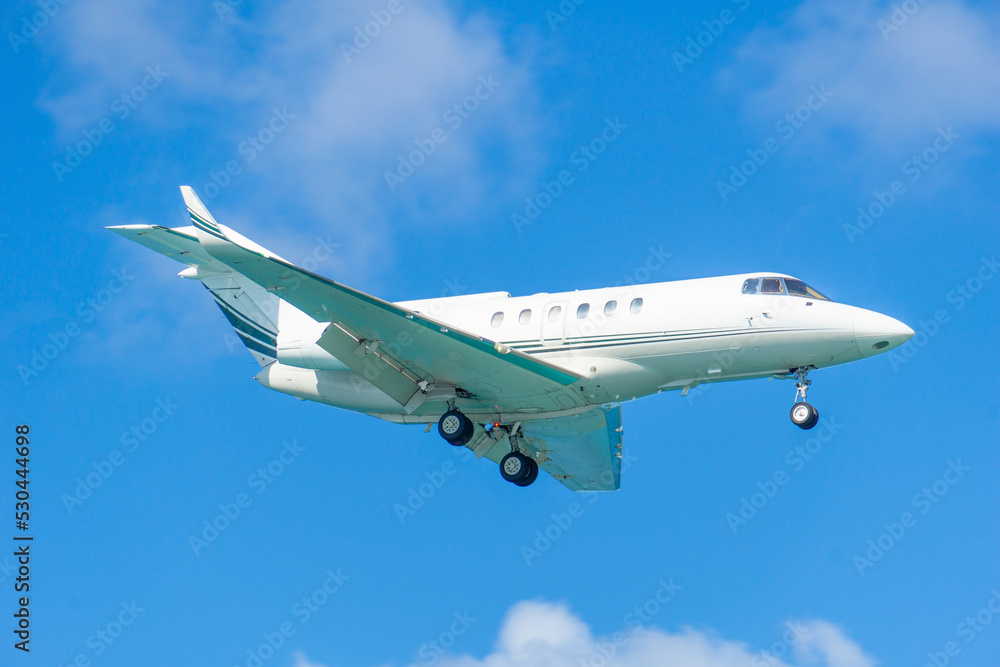 A blurry private jet comes in for a landing. The jet plane released the landing gear. Small private plane in the sky.