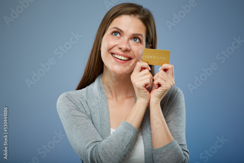 Woman with credit card dreaming and looking up isolated portrait.