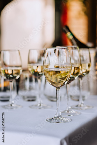 A lot, a row of glass glasses with champagne stands on the table.