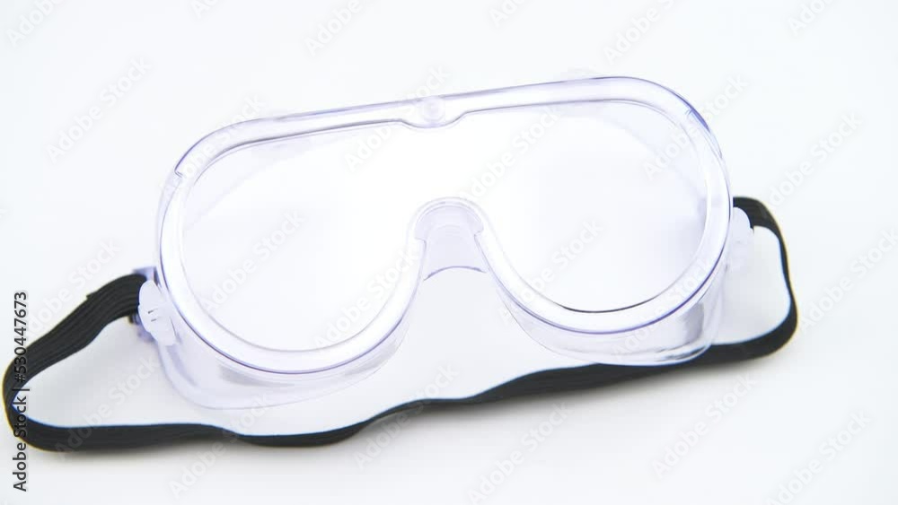 Macro closeup of hand holding safety industrial goggles, transparent eyeglasses eyewear isolated against white background kitchen table Macro closeup of hand holding safety industrial goggles, transparent eyeglasses eyewear isolated against white background kitchen table