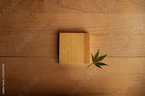 CBD. A woodcut lies on a trendy wooden background next to a cannabis leaf. Wooden platform for the presentation of luxury and natural cosmetics or products photo