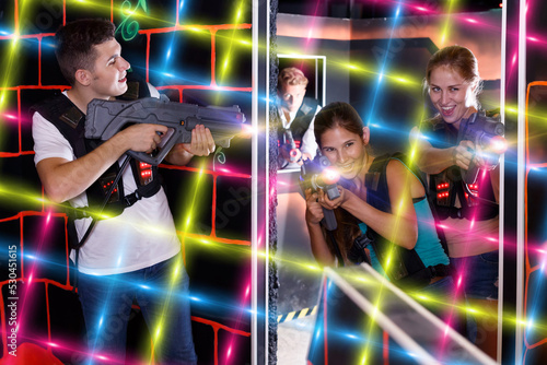 Friendly players young mens and womens playing in teams in dark laser tag station