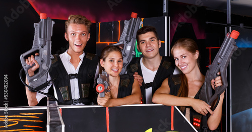 Group portrait of command players with pistols in their hands in dark laser tag room
