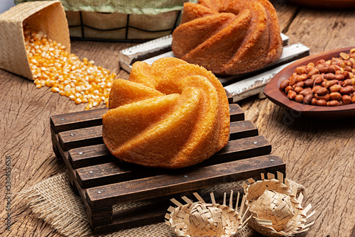 Homemade cornmeal cake made from corn on a mini dark wooden pallet on a rustic wooden table with other typical sweets from Festa Junina, a typical Brazilian festival photo