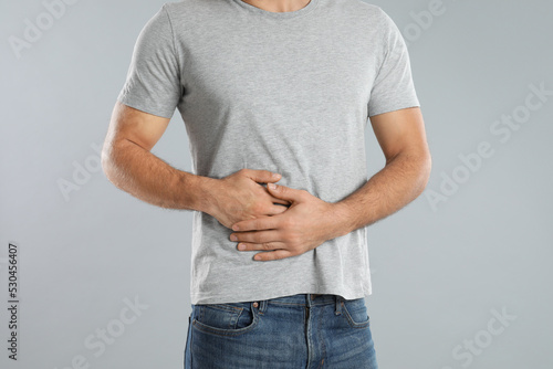 Man suffering from liver pain on grey background, closeup