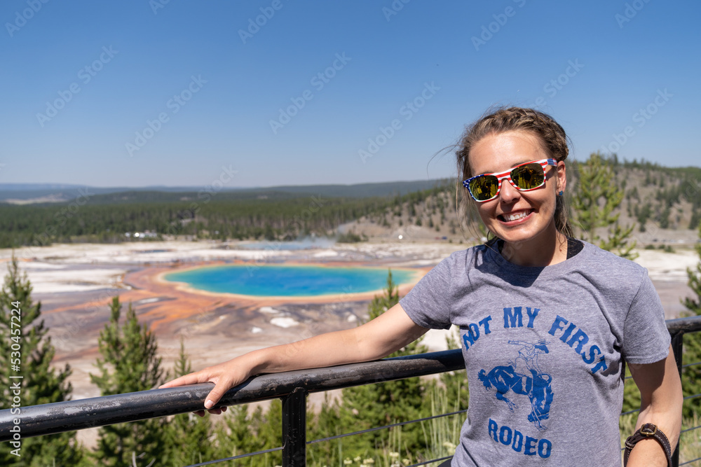 Cute woman tourist poses at the overlook for Grand Prismatic Spring in Yellowstone National Park