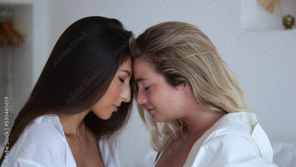 Two girlfriends love each other, they have a real female understanding, the women are sitting together on the bed in the bedroom, the blonde and the brunette leaned their foreheads. Two girlfriends love each other, they have a real female understanding, the women are sitting together on the bed in the bedroom, the blonde and the brunette leaned their foreheads.